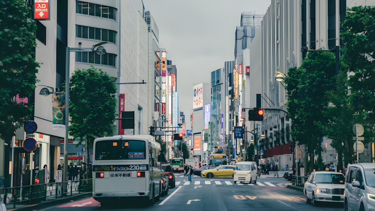 A wide-angle view of a modern smart city intersection at dusk. Traffic lights, surveillance cameras, and connected street infrastructure are visible. Subtle digital network lines or glowing data paths overlay the scene, visually connecting poles, signals, and roadside units. No chaos - just structured, intelligent infrastructure operating smoothly.